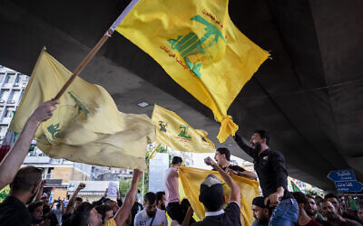 Illustrative: Hezbollah and Amal supporters wave Hezbollah and Iranian flags as they shout slogans against Israel and the US during a protest in the southern suburb of Beirut, Lebanon, June 28, 2020. (AP Photo/Hassan Ammar)