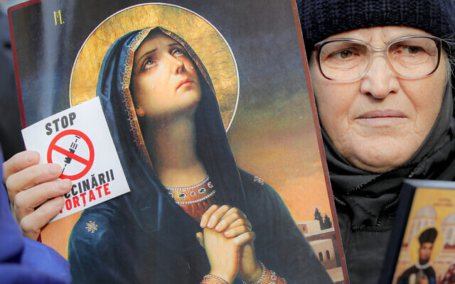 An anti-vaccination protester holds a sticker that reads 'Stop the Mandatory Vaccination' next to an icon during a rally in Bucharest, Romania,, March 20, 2021. (Vadim Ghirda/AP) An anti-vaccination protester holds a sticker that reads 'Stop the Mandatory Vaccination' next to an icon during a rally in Bucharest, Romania,, March 20, 2021. (Vadim Ghirda/AP)