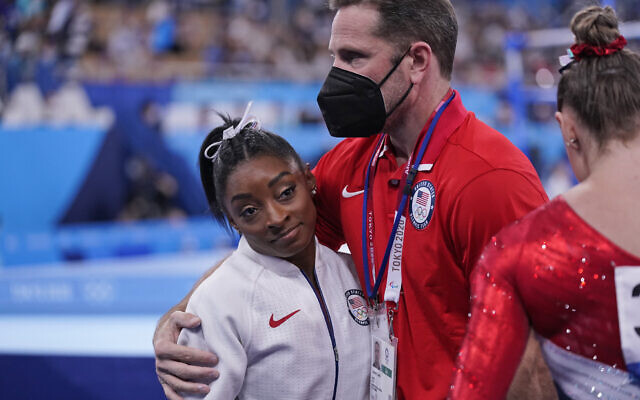 Coach Laurent Landi embraces Simone Biles, after she exited the team final with apparent injury, at the 2020 Summer Olympics, July 27, 2021, in Tokyo. (AP Photo/Gregory Bull) Coach Laurent Landi embraces Simone Biles, after she exited the team final with apparent injury, at the 2020 Summer Olympics, July 27, 2021, in Tokyo. (AP Photo/Gregory Bull)