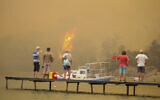 Tourists wait to be evacuated from smoke-engulfed Mazi area as wildfires rolled down the hill toward the seashore, in Bodrum, Mugla, Turkey, Sunday, Aug. 1, 2021. (AP Photo/Emre Tazegul)