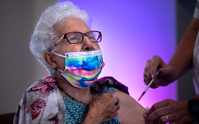 Rachel Gershon, 83, receives a third Pfizer-BioNTech COVID-19 vaccine from a Magen David Adom national emergency service volunteer, at a private nursing home, in Netanya, August 1, 2021. (AP Photo/Oded Balilty)