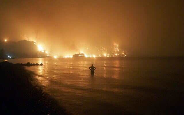 A man watches as wildfires approach Kochyli beach near Limni village on the island of Evia, about 160 kilometers (100 miles) north of Athens, Greece, August 6, 2021. (AP Photo/Thodoris Nikolaou, file) A man watches as wildfires approach Kochyli beach near Limni village on the island of Evia, about 160 kilometers (100 miles) north of Athens, Greece, August 6, 2021. (AP Photo/Thodoris Nikolaou, file)