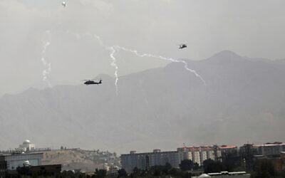 Anti-missile decoy flares are deployed as U.S. Black Hawk military helicopters and a dirigible balloon fly over the city of Kabul, Afghanistan, Sunday, Aug. 15, 2021. (AP/Rahmat Gul)