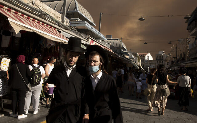 Ultra-Orthodox Jews walk through the Machane Yehuda market under a sky darkened by nearby wildfires, in Jerusalem, Aug. 15, 2021.(AP Photo/Maya Alleruzzo) Ultra-Orthodox Jews walk through the Machane Yehuda market under a sky darkened by nearby wildfires, in Jerusalem, Aug. 15, 2021.(AP Photo/Maya Alleruzzo)