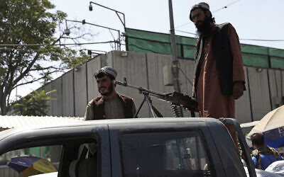 Taliban fighters stand guard on the back of vehicle with a machine gun in front of main gate leading to Afghan presidential palace, in Kabul, Afghanistan, August 16, 2021.(AP/Rahmat Gul)