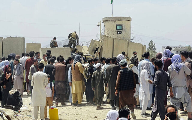 Afghan security guards stand on a wall as hundreds of people gather outside the international airport in Kabul, Afghanistan, on Tuesday, August 17, 2021. (AP) Afghan security guards stand on a wall as hundreds of people gather outside the international airport in Kabul, Afghanistan, on Tuesday, August 17, 2021. (AP)