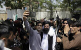 An Afghan takes a selfie with Taliban fighters on patrol in Kabul, Afghanistan, on August 19, 2021. (AP/Rahmat Gul)