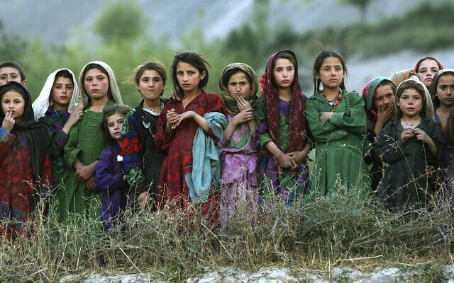 Local girls look at UN workers unloading ballot kits from a U.N. helicopter in Ghumaipayan Mahnow village, some 410 kilometers (256 miles) northeast of Kabul, Afghanistan, Monday, Oct. 4, 2004. By air is the only way to deliver the electoral material in the inaccessible areas of the Badakhshan province. (AP Photo/Emilio Morenatti)