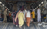 In this image provided by the US Air Force, a US Air Force loadmaster, assigned to the 816th Expeditionary Airlift Squadron, assists evacuees aboard a C-17 Globemaster III aircraft in support of Operation Allies Refuge at Hamid Karzai International Airport in Kabul, Afghanistan, August 20, 2021. (Senior Airman Taylor Crul/US Air Force via AP)
