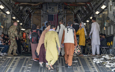 In this image provided by the US Air Force, a US Air Force loadmaster, assigned to the 816th Expeditionary Airlift Squadron, assists evacuees aboard a C-17 Globemaster III aircraft in support of Operation Allies Refuge at Hamid Karzai International Airport in Kabul, Afghanistan, August 20, 2021. (Senior Airman Taylor Crul/US Air Force via AP)