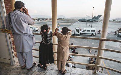 In this image provided by the US Marine Corps, two children point at an aircraft after they have been manifested to depart, at Hamid Karzai International Airport, Kabul, Afghanistan, August 21, 2021. (1st Lt. Mark Andries/U.S. Marine Corps via AP)