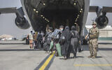 In this image provided by the US Marine Corps, families begin to board a US Air Force Boeing C-17 Globemaster III during an evacuation at Hamid Karzai International Airport in Kabul, Afghanistan, on August 23, 2021. (Sgt. Samuel Ruiz/US Marine Corps via AP)