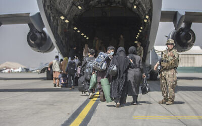 In this image provided by the US Marine Corps, families begin to board a US Air Force Boeing C-17 Globemaster III during an evacuation at Hamid Karzai International Airport in Kabul, Afghanistan, on August 23, 2021. (Sgt. Samuel Ruiz/US Marine Corps via AP)
