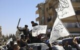 Members of the Hay'at Tahrir al-Sham, a Sunni Islamist militant group, wave the Taliban flags as they celebrate the Taliban takeover of Afghanistan, in the city of Idlib, Friday, Aug. 20, 2021 (AP Photo/Ghaith Alsayed)