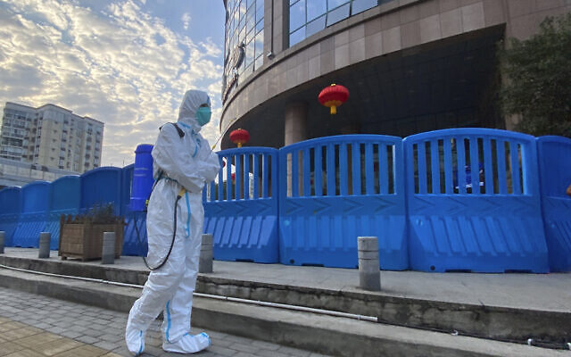 In this Feb. 6, 2021 photo, a worker in protective overalls carries disinfecting equipment while walking outside the Wuhan Central Hospital, where Li Wenliang, the whistleblower doctor who sounded the alarm and was reprimanded by local police for it in the early days of Wuhan's pandemic, worked in Wuhan in central China. (AP/Ng Han Guan) In this Feb. 6, 2021 photo, a worker in protective overalls carries disinfecting equipment while walking outside the Wuhan Central Hospital, where Li Wenliang, the whistleblower doctor who sounded the alarm and was reprimanded by local police for it in the early days of Wuhan's pandemic, worked in Wuhan in central China. (AP/Ng Han Guan)