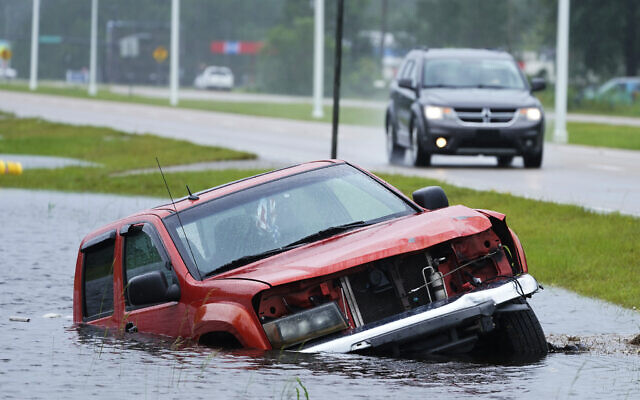 An abandoned vehicle is half submerged in a ditch next to a near flooded highway as the outer bands of Hurricane Ida arrive Sunday, Aug. 29, 2021, in Bay Saint Louis, Miss. (AP Photo/Steve Helber) An abandoned vehicle is half submerged in a ditch next to a near flooded highway as the outer bands of Hurricane Ida arrive Sunday, Aug. 29, 2021, in Bay Saint Louis, Miss. (AP Photo/Steve Helber)