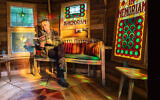 Les Rowe sits amid panels from a Cardiff synagogue in his 'Tranquility Base' shed. (Cuprinol via JTA)