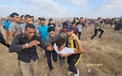 Palestinians carry a demonstrator wounded during clashes with Israeli soldiers along the Gaza border, on Saturday, August 21, 2021. (Credit: Hassan Islayeh)
