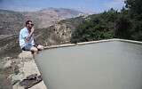 A man sits in a water spring in the Golan Heights, northern Israel, during the summer vacation, on August 6, 2021. (Michael Giladi/Flash90)
