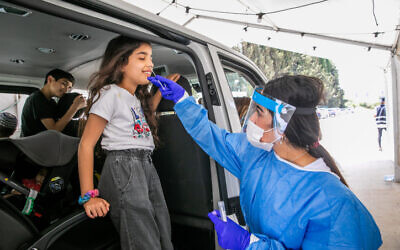A medical worker takes a samples from a young Israeli at a drive through complex to check if they have been infected with the coronavirus (Yossi Aloni/Flash90)