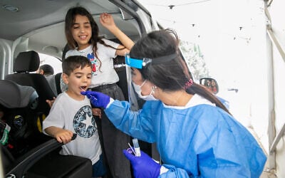 Health care workers take test samples of Israelis in a drive through complex in Rehovot to check if they have been infected with the coronavirus, on August 8, 2021. (Yossi Aloni/Flash90)