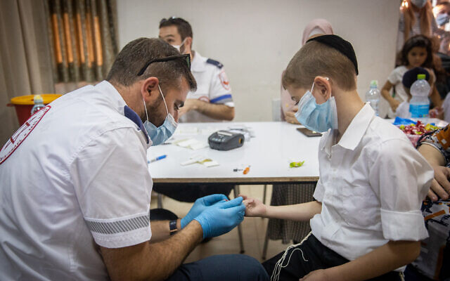 A Magen David Adom paramedic takes blood for serological tests on ultra-Orthodox school kids in Kiryat Yearim on August 9, 2021. (Yonatan Sindel/Flash90) A Magen David Adom paramedic takes blood for serological tests on ultra-Orthodox school kids in Kiryat Yearim on August 9, 2021. (Yonatan Sindel/Flash90)