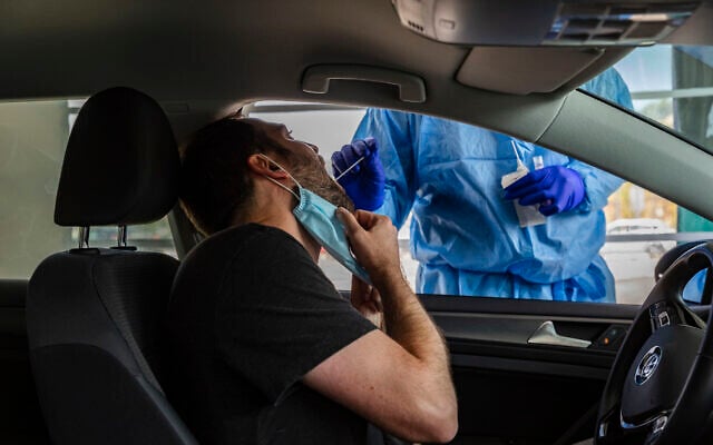 A healthcare worker takes a swab sample from a man at a drive-thru coronavirus testing facility in Jerusalem, on August 10, 2021. (Olivier Fitoussi/Flash90) A healthcare worker takes a swab sample from a man at a drive-thru coronavirus testing facility in Jerusalem, on August 10, 2021. (Olivier Fitoussi/Flash90)