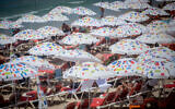 Israelis enjoy the beach in Tel Aviv on a hot summer day. August 11, 2021. (Miriam Alster/Flash90)