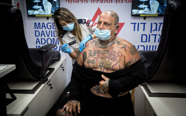 An Israeli man receives a COVID-19 vaccine during a mass vaccination drive at Dizengoff Square in Tel Aviv, on the night of August 14, 2021. (Miriam Alster/Flash90) An Israeli man receives a COVID-19 vaccine during a mass vaccination drive at Dizengoff Square in Tel Aviv, on the night of August 14, 2021. (Miriam Alster/Flash90)