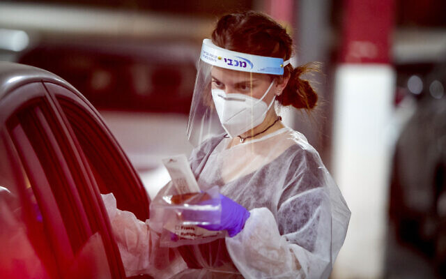A healthcare worker examines a COVID test sample at a drive-through facility in Modi'in, on August 15 2021. (Yossi Aloni/Flash90) A healthcare worker examines a COVID test sample at a drive-through facility in Modi'in, on August 15 2021. (Yossi Aloni/Flash90)