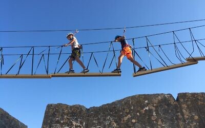 Walking across a hanging bridge in the Tower of David Museum ropes course, August 2021 (Jessica Steinberg/Times of Israel)