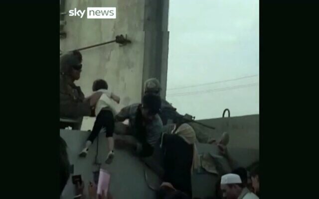 A soldier at Kabul Airport lifts a young child in a Sky News report from Afghanistan, August 19, 2021 (Screenshot) A soldier at Kabul Airport lifts a young child in a Sky News report from Afghanistan, August 19, 2021 (Screenshot)