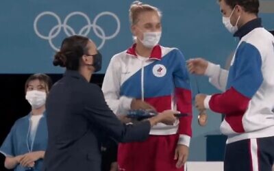 Russia's Aslan Karatsev attempts to give a gold medal to his mixed doubles tennis partner Russia's Elena Vesnina during the Tokyo 2020 Olympic medal ceremony at the Ariake Tennis Park on August 1, 2021. They actually won the silver medals (Twitter screenshot)