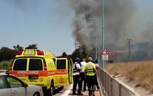Paramedics look on as smoke rises from the scene where rocket landed near the northern city of Kiryat Shmona, on August 4, 2021. (Magen David Adom) Paramedics look on as smoke rises from the scene where rocket landed near the northern city of Kiryat Shmona, on August 4, 2021. (Magen David Adom)