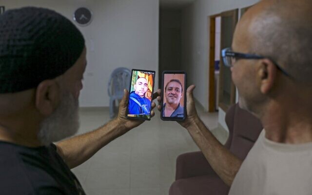 Malek Hassuna (L) carries a picture of his late son Mussa, who was shot dead on May 10, and Effi Yehoshua (R) carries a picture of his late brother Yigal, who was killed when a rain of stones hit his car on May 11, as they pose for a picture in Lod on August 18, 2021. (AHMAD GHARABLI / AFP) Malek Hassuna (L) carries a picture of his late son Mussa, who was shot dead on May 10, and Effi Yehoshua (R) carries a picture of his late brother Yigal, who was killed when a rain of stones hit his car on May 11, as they pose for a picture in Lod on August 18, 2021. (AHMAD GHARABLI / AFP)