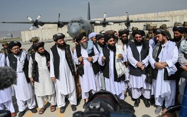 Taliban spokesman Zabihullah Mujahid (C, with shawl) speaks to the media at the airport in Kabul on August 31, 2021. (WAKIL KOHSAR / AFP) Taliban spokesman Zabihullah Mujahid (C, with shawl) speaks to the media at the airport in Kabul on August 31, 2021. (WAKIL KOHSAR / AFP)