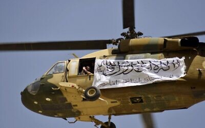 A helicopter displaying a Taliban flag fly above of supporters gathered to celebrate the US withdrawal of all its troops out of Afghanistan, in Kandahar on September 1, 2021. (JAVED TANVEER / AFP)
