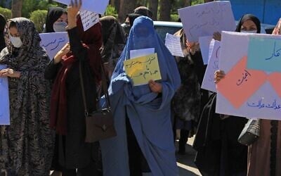 Afghan women hold placards and don burkas as they take part in a protest in Herat on September 2, 2021. (AFP)
