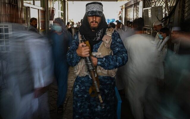 A Taliban fighter stands guard as people move past him at a market with currency exchange shops in Kabul on September 5, 2021. (Aamir Qureshi/AFP) A Taliban fighter stands guard as people move past him at a market with currency exchange shops in Kabul on September 5, 2021. (Aamir Qureshi/AFP)