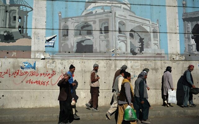 Afghan workers walk past a wall mural along a roadside in Kabul on September 5, 2021. (HOSHANG HASHIMI / AFP) Afghan workers walk past a wall mural along a roadside in Kabul on September 5, 2021. (HOSHANG HASHIMI / AFP)