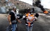 A Palestinian protester carries a young boy away from the scene of confrontations with Israeli security forces, following a demonstration against settlements in the West Bank village of Beita, on September 17, 2021. (JAAFAR ASHTIYEH / AFP)