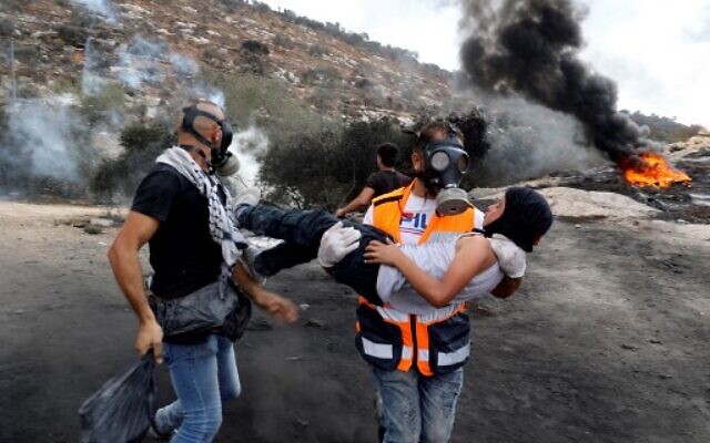 A Palestinian protester carries a young boy away from the scene of confrontations with Israeli security forces, following a demonstration against settlements in the West Bank village of Beita, on September 17, 2021. (JAAFAR ASHTIYEH / AFP) A Palestinian protester carries a young boy away from the scene of confrontations with Israeli security forces, following a demonstration against settlements in the West Bank village of Beita, on September 17, 2021. (JAAFAR ASHTIYEH / AFP)