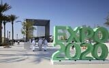 People walk past the official Expo 2020 sign at the Dubai Expo in the United Arab Emirates, January 16, 2021. (Photo by Karim SAHIB / AFP)