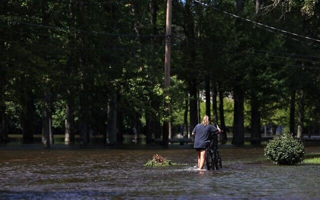 A girl walks a bike along a flooded West Williams Street, on September 2, 2021, in Lincoln Park, New Jersey. (Michael M. Santiago/Getty Images/AFP)