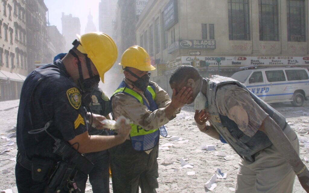 Police officers help rinse a man's eyes after the fall of the Twin Towers on September 11, 2001, in New York City. (AP Photo/Shawn Baldwin)