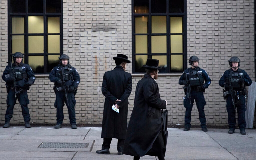 In this illustrative photo from December 11, 2019, Orthodox Jewish men pass by New York City police guarding a Brooklyn synagogue prior to a funeral for Mosche Deutsch, a rabbinical student from Brooklyn who was killed in a shooting at a Jersey City, New Jersey market. (AP Photo/Mark Lennihan, File) In this illustrative photo from December 11, 2019, Orthodox Jewish men pass by New York City police guarding a Brooklyn synagogue prior to a funeral for Mosche Deutsch, a rabbinical student from Brooklyn who was killed in a shooting at a Jersey City, New Jersey market. (AP Photo/Mark Lennihan, File)
