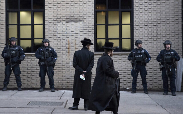 In this illustrative photo from December 11, 2019, Orthodox Jewish men pass by New York City police guarding a Brooklyn synagogue prior to a funeral for Mosche Deutsch, a rabbinical student from Brooklyn who was killed in a shooting at a Jersey City, New Jersey market. (AP Photo/Mark Lennihan, File) In this illustrative photo from December 11, 2019, Orthodox Jewish men pass by New York City police guarding a Brooklyn synagogue prior to a funeral for Mosche Deutsch, a rabbinical student from Brooklyn who was killed in a shooting at a Jersey City, New Jersey market. (AP Photo/Mark Lennihan, File)