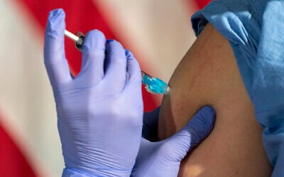 Illustrative image: In front of an American flag, nurse Lillian Wirpsza (left) administers a COVID-19 vaccine to Shylee Stewart, a labor and delivery nurse at George Washington University Hospital. (AP Photo/Jacquelyn Martin, Pool)