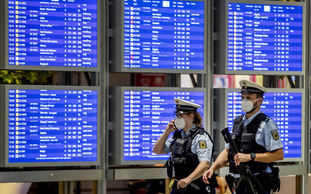 Illustrative: German police officers wearing face mask walk past a flight board in a terminal at the airport in Frankfurt, Germany, on May 11, 2021. (AP/Michael Probst) Illustrative: German police officers wearing face mask walk past a flight board in a terminal at the airport in Frankfurt, Germany, on May 11, 2021. (AP/Michael Probst)