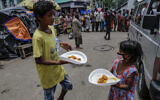 Children living in a slum receive a free meal distributed by a voluntary organization during a coronavirus lockdown in Kolkata, India, June 2, 2021. (AP Photo/Bikas Das)